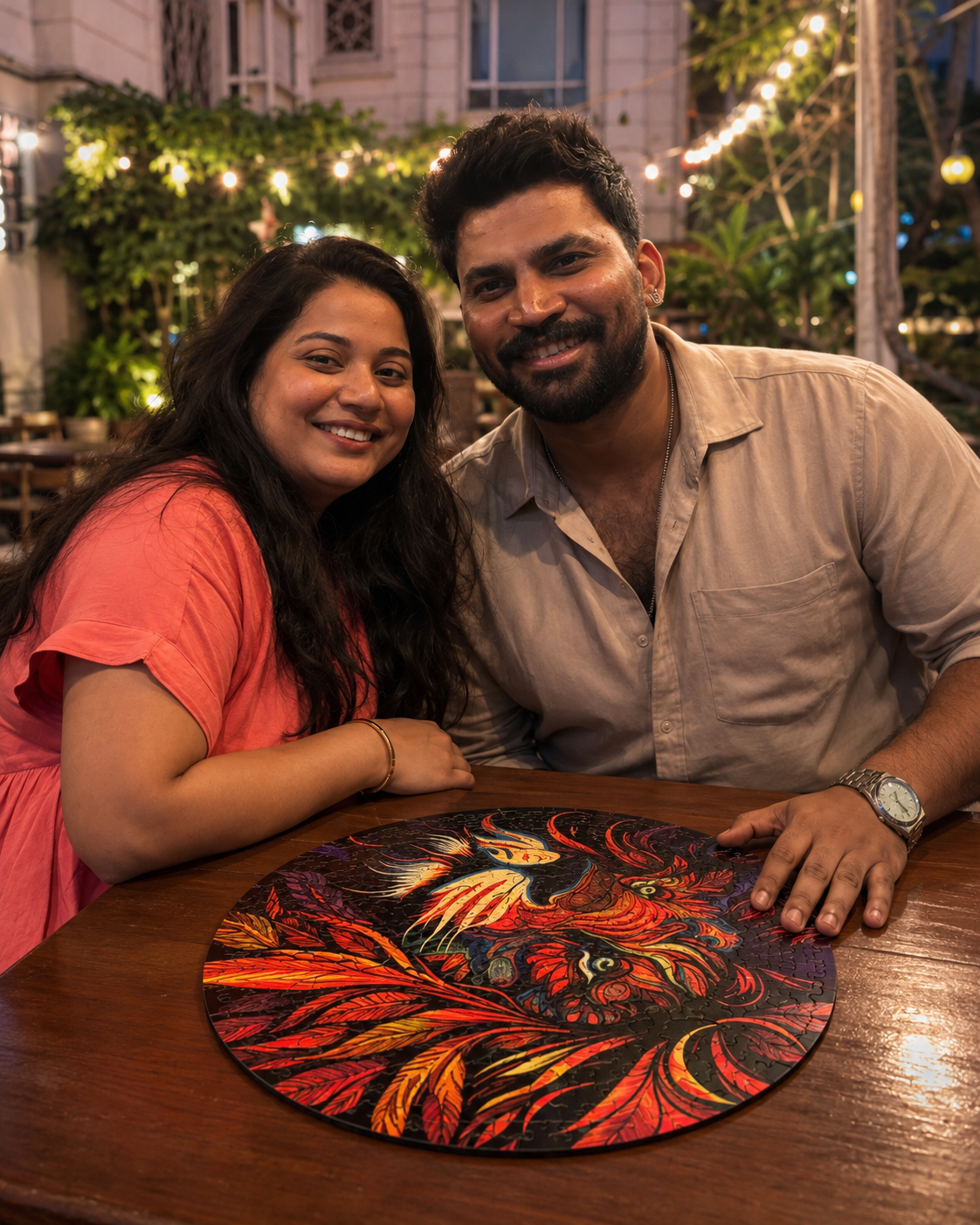 A couple smiling at a wooden table in a restaurant setting, with a round decorative placemat featuring a fiery red, orange, and yellow tiger design in the foreground.