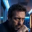 A close-up shot of a man's face showing a serious, contemplative expression, set against a dark background with blue lighting.